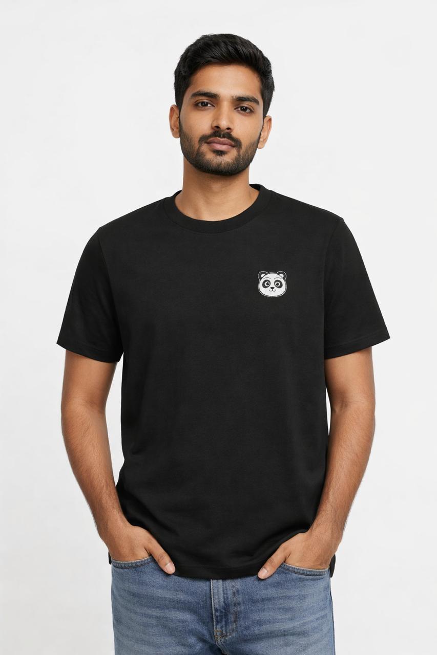 Man wearing a black t-shirt with a small panda logo on a plain background